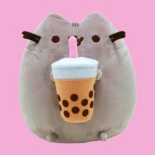 Pusheen the cat can't resist a yummy boba tea! This gorgeous plush kitty is holding a cup of boba tea with a pink straw in between her front paws.